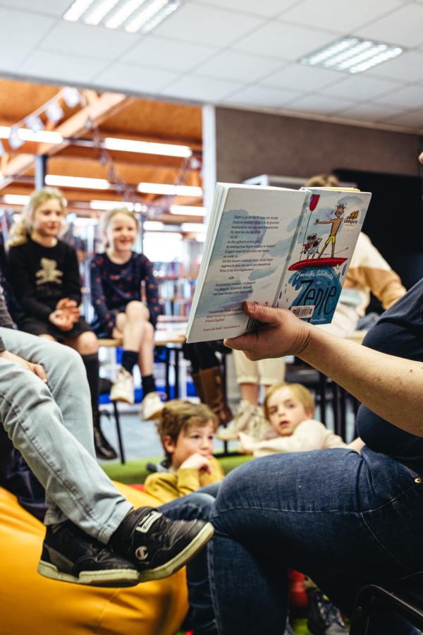 een begeleider toont een boek aan een leesgroep
