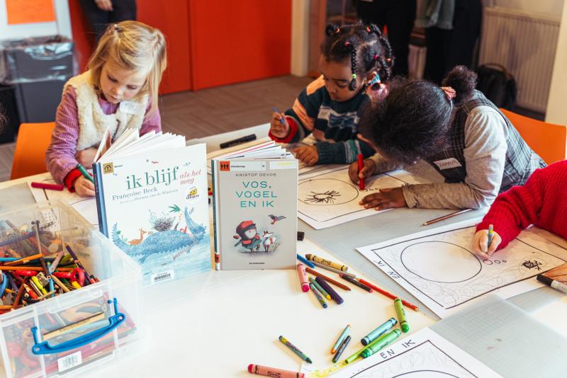 een groepje kinderen werkt aan tafel aan tekeningen bij twee Leesjury-boeken